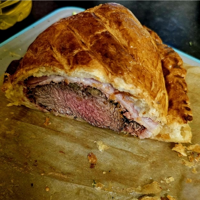 Golden mini beef Wellington served on a plate with flaky puff pastry, tender beef, and savory mushroom filling.