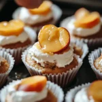 Honey Peach Cream Cheese Cupcakes beautifully frosted and topped with peach slices, honey drizzle, and edible flowers, displayed on a white plate.