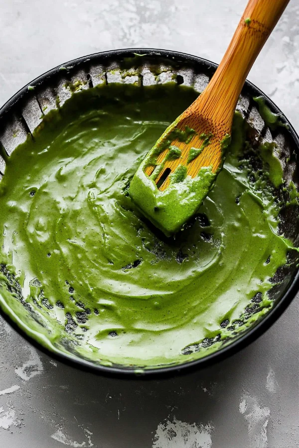 Flat lay of ingredients for matcha brownies, including matcha powder, white chocolate, and eggs.